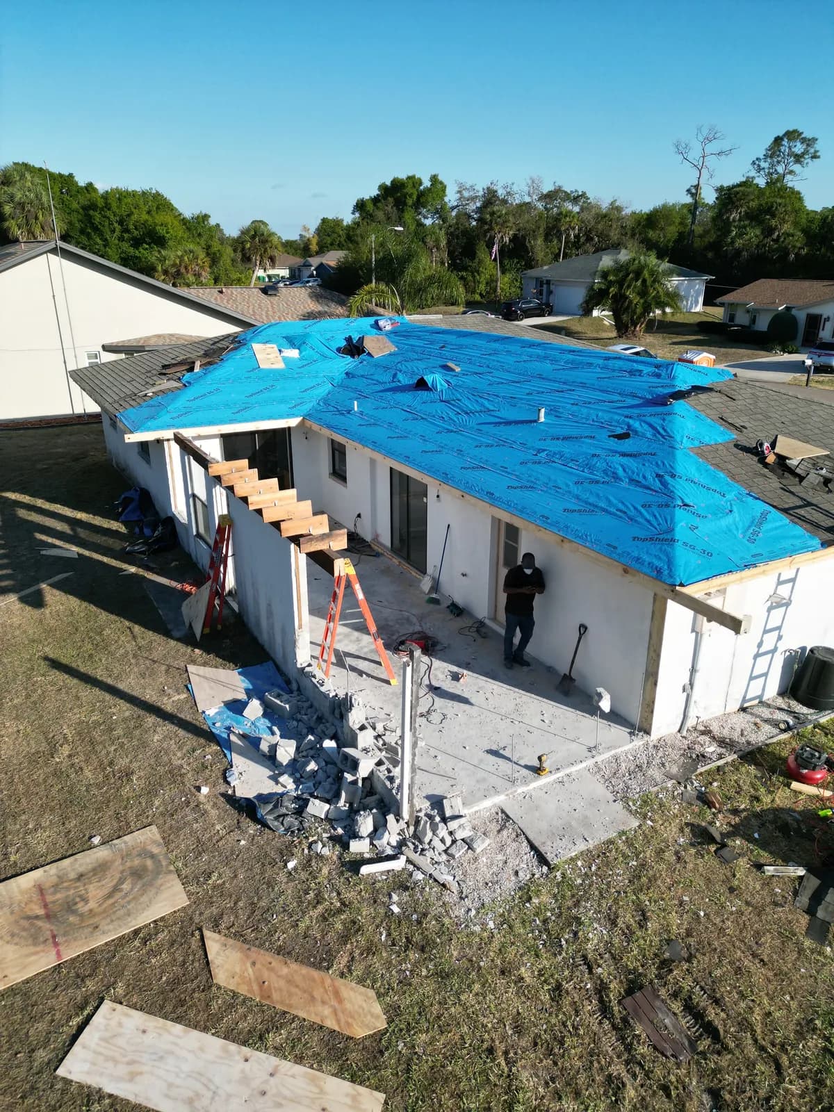 Storm-damaged roof protected with blue tarp before replacement